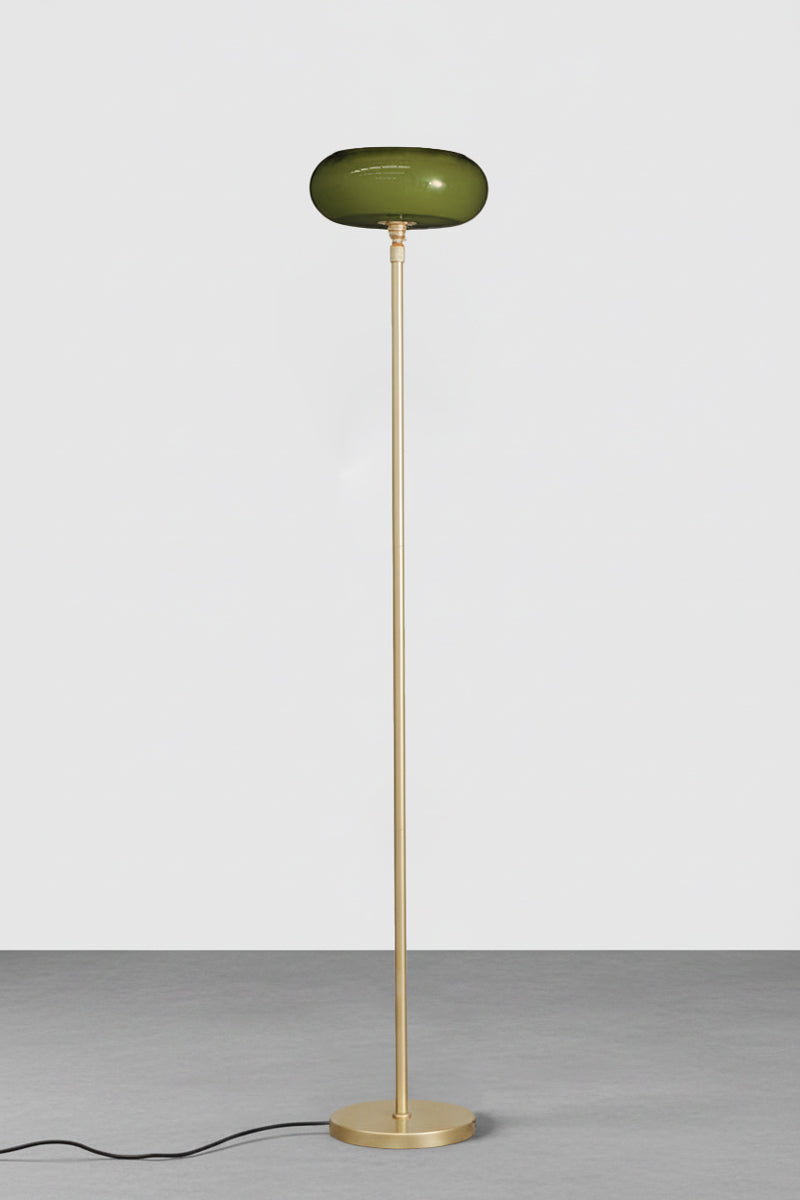 An forest green glass shade on a slim gold brass metal stand, shown against a solid light gray background.
