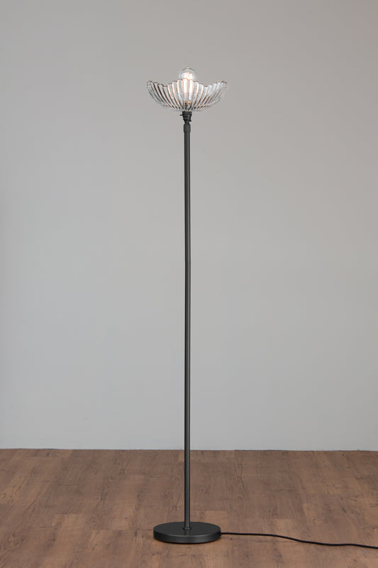 Hepburn Glass Floor Lamp with a black stand and art deco inspired clear glass shade on a timber floor. 