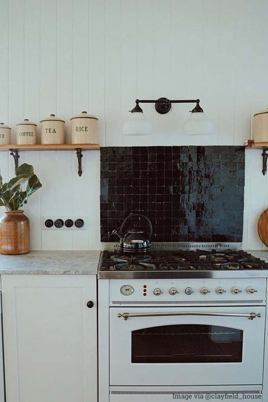Double black arm wall light with opal shades hanging above a stove.
