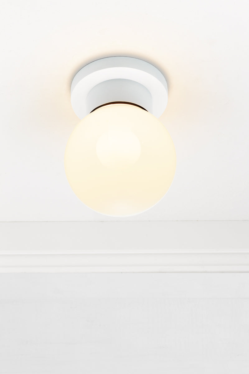 Ceiling mounted Bunker globe light with a white fixture and opal glass ball shade. 