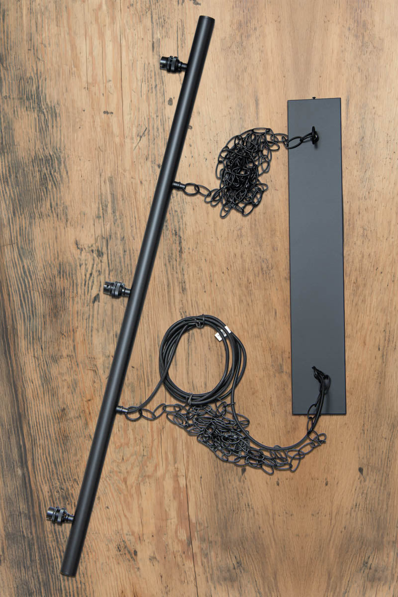 Metal bar with chain and cord suspension, uninstalled on a timber bench.