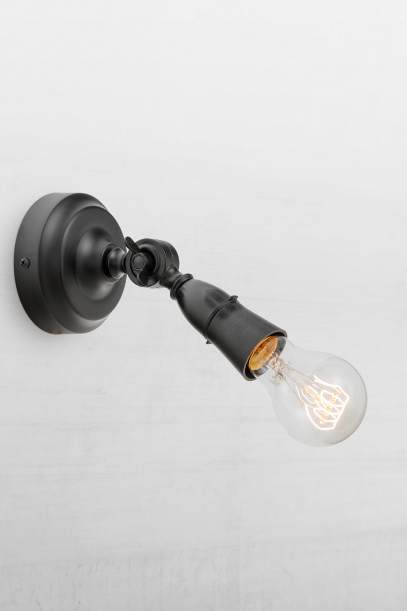 Black batten holder with adjustable lampholder tilted outwards. 