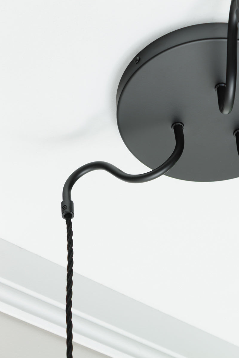 Close up of the matt black round ceiling rose and gooseneck arm of the suspension. 
