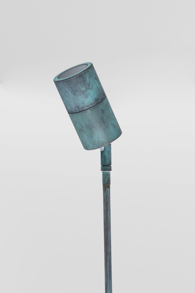 Solid brass spike light with a green patina finish