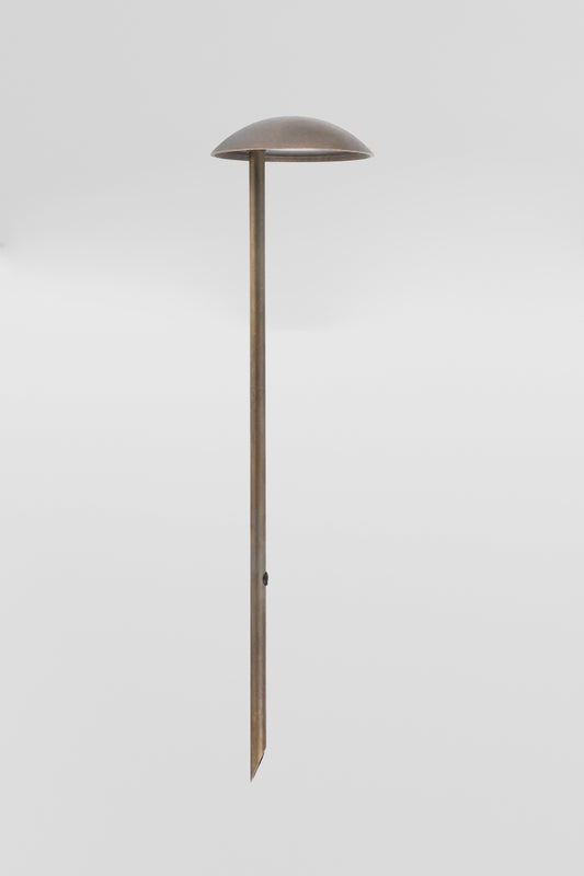 Brass garden spike with built in LED light source and curved hood shade. 
