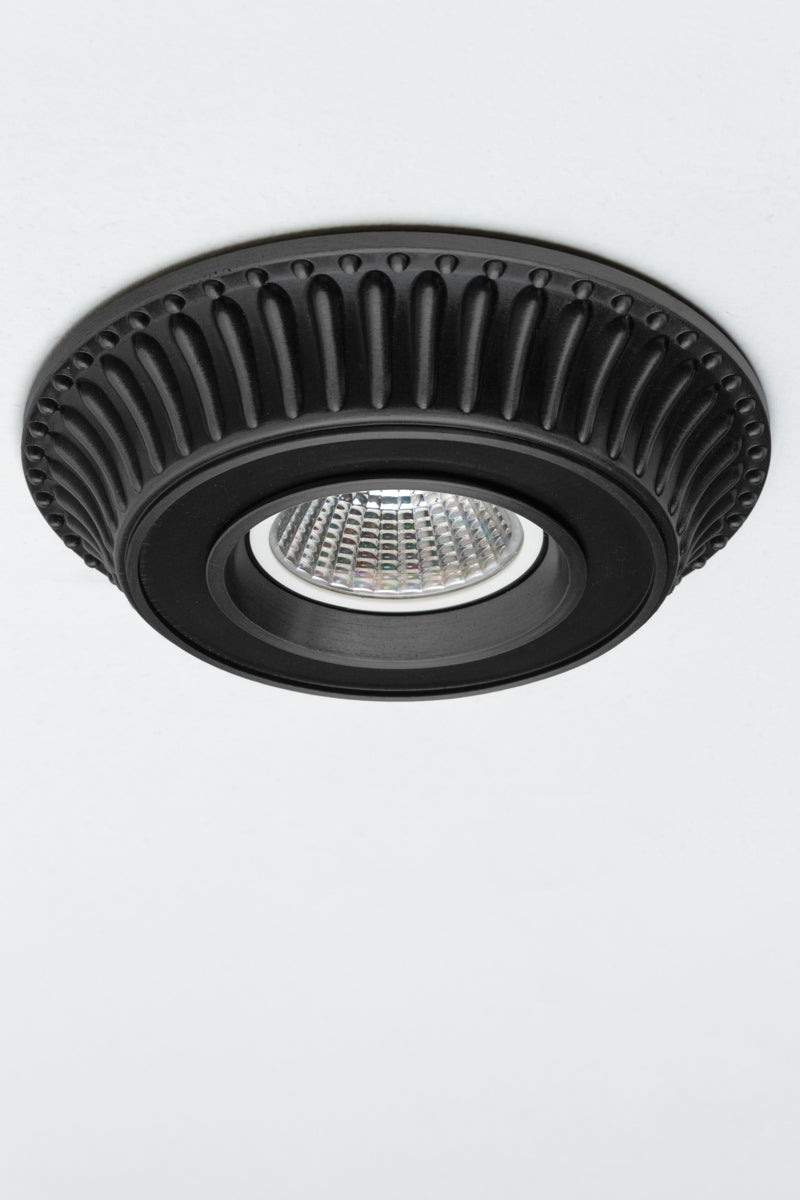 Black finish on a cast brass recessed ceiling light. Fluted detailing along the outer rim