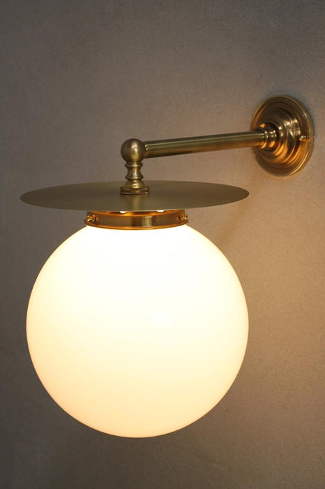gold/brass disc wall light with opal ball shade