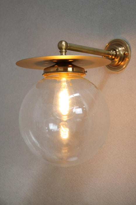 gold/brass disc wall light with clear ball shade