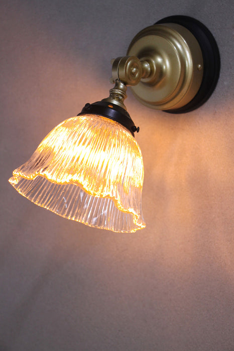 Gold sconce with black mounting block and small frill shade