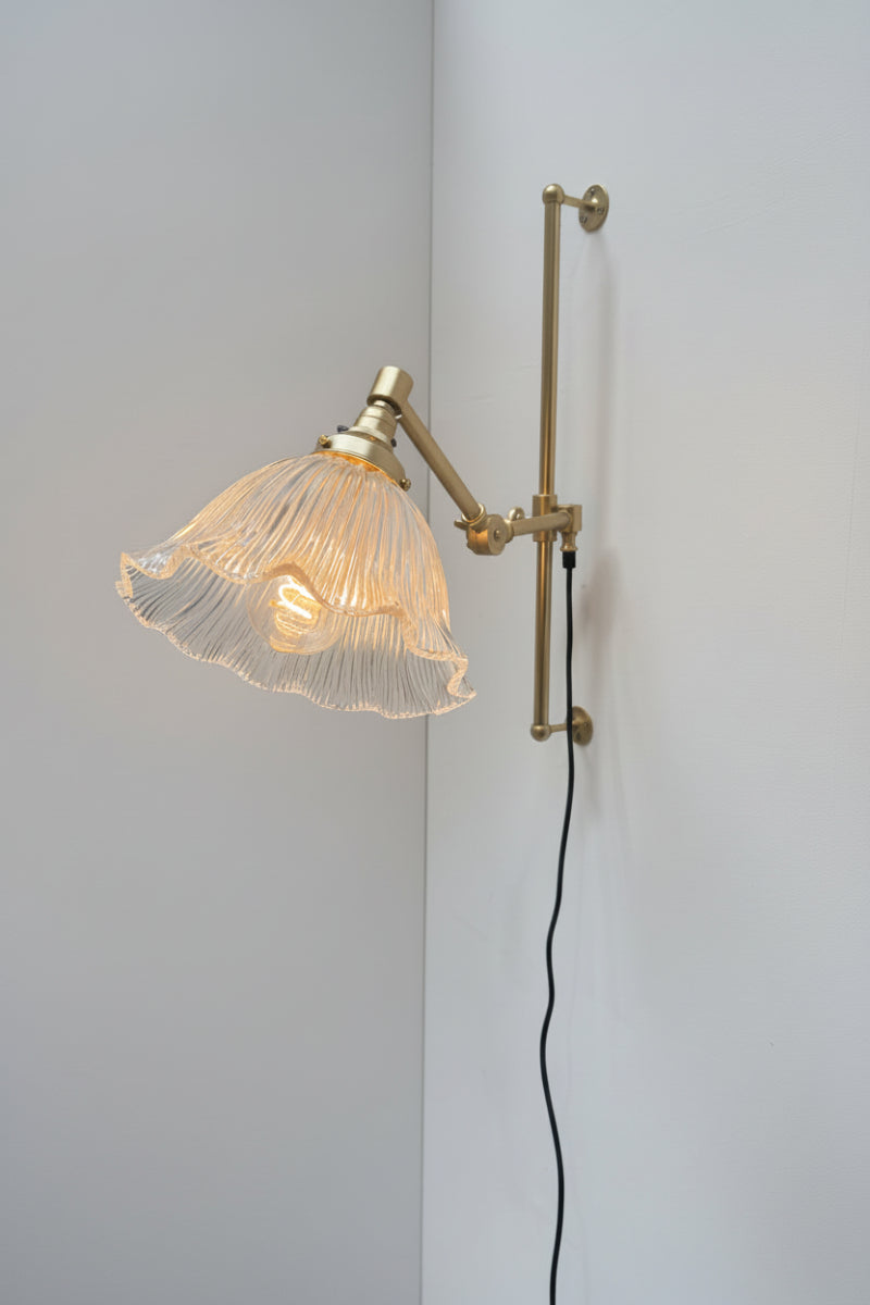 Large ribbed clear glass shade with a frilled edge, paired with a gold/brass wall fixture