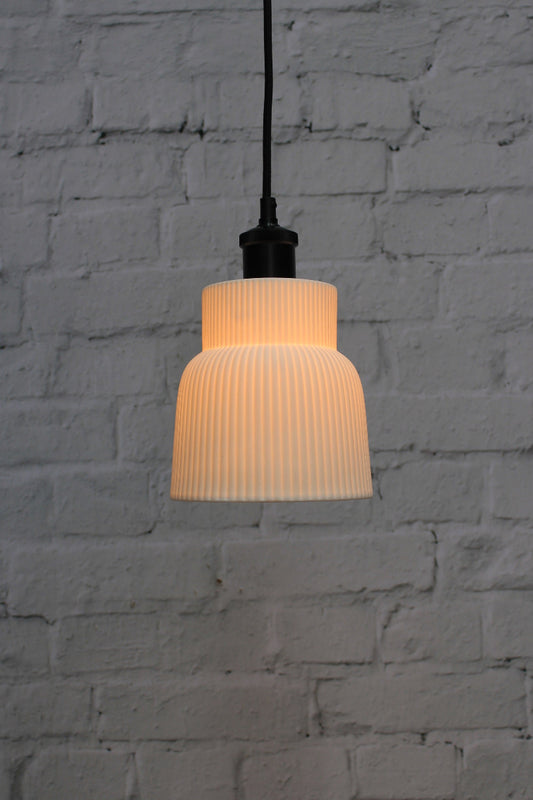 Ceramic pendant light with ribbed design against a textured gray wall