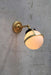 Huxley wall light with long gold arm and small opal shade in tilted position