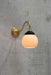 steel gooseneck wall light in gold/ brass finish with small opal shade