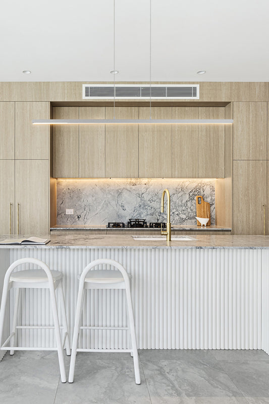 Linear LED pendant light in white above a white and timeber kitchen.. 