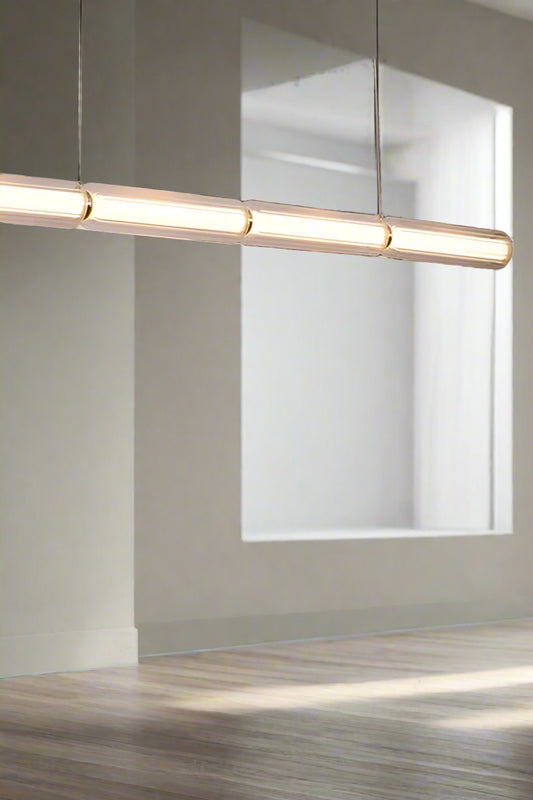 LED linear pendant light in gold in a dining/living space.