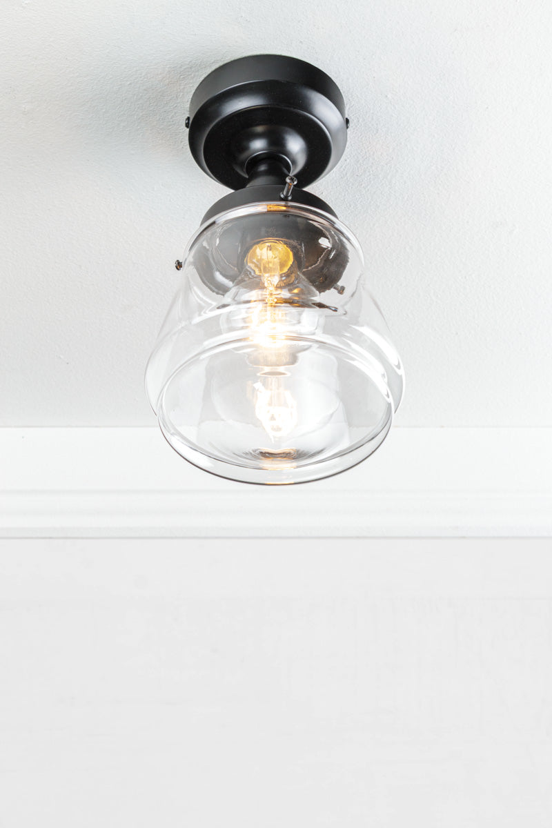 Black batten holder paired with a clear glass shade on a white ceiling. 