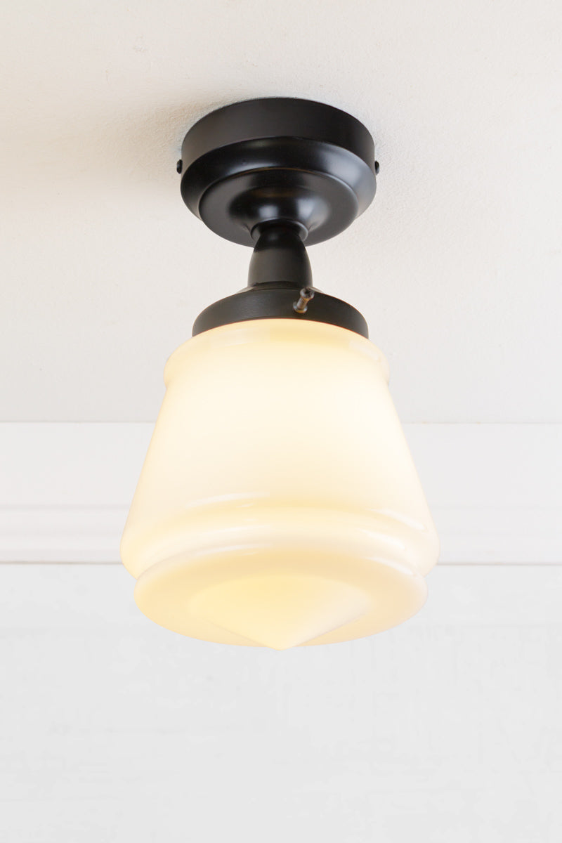 Black batten holder paired with a n opal glass shade on a white ceiling. 