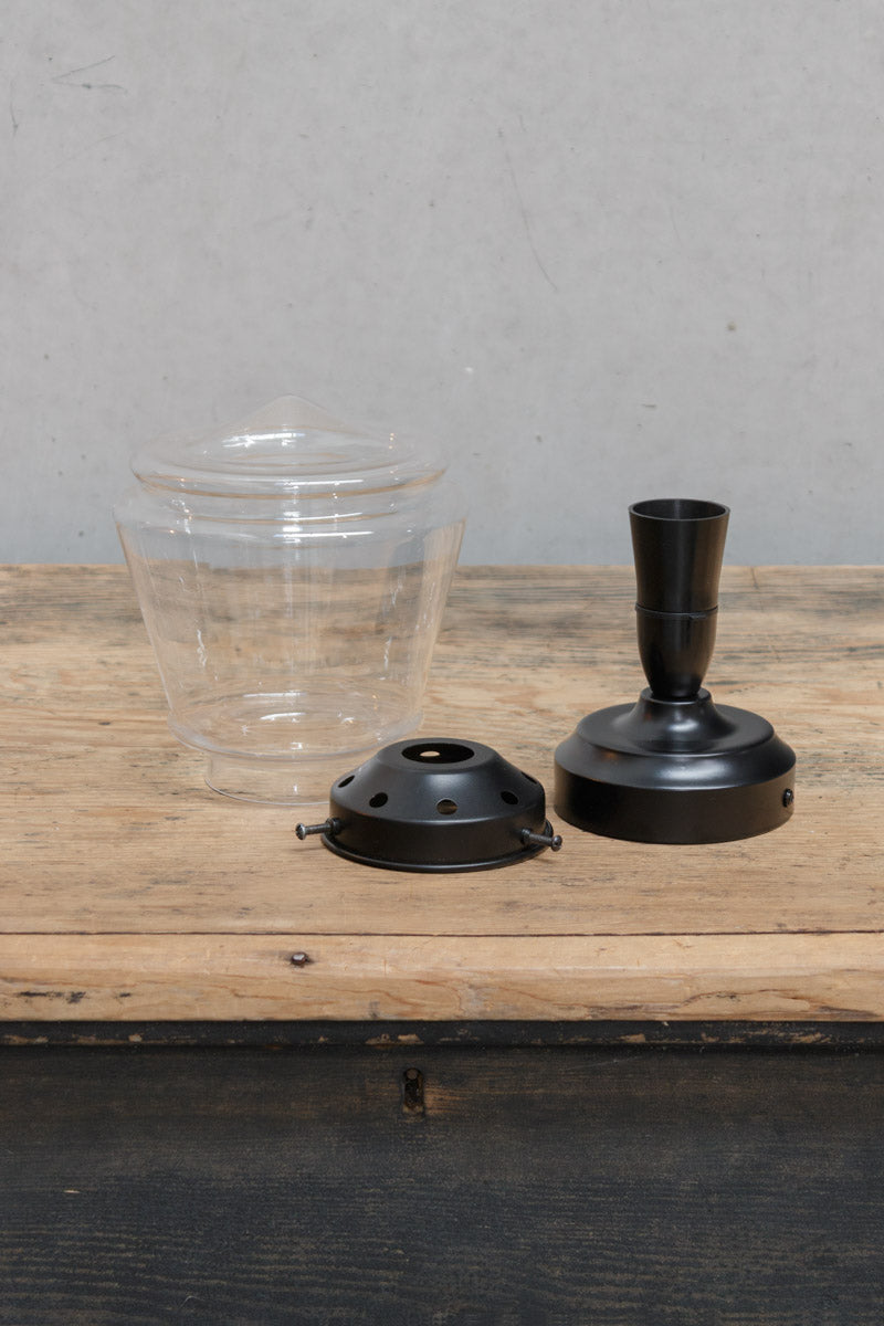 Uninstalled ceiling light KIT with a clear deco shade, black gallery and black batten holder on a timber bench. 