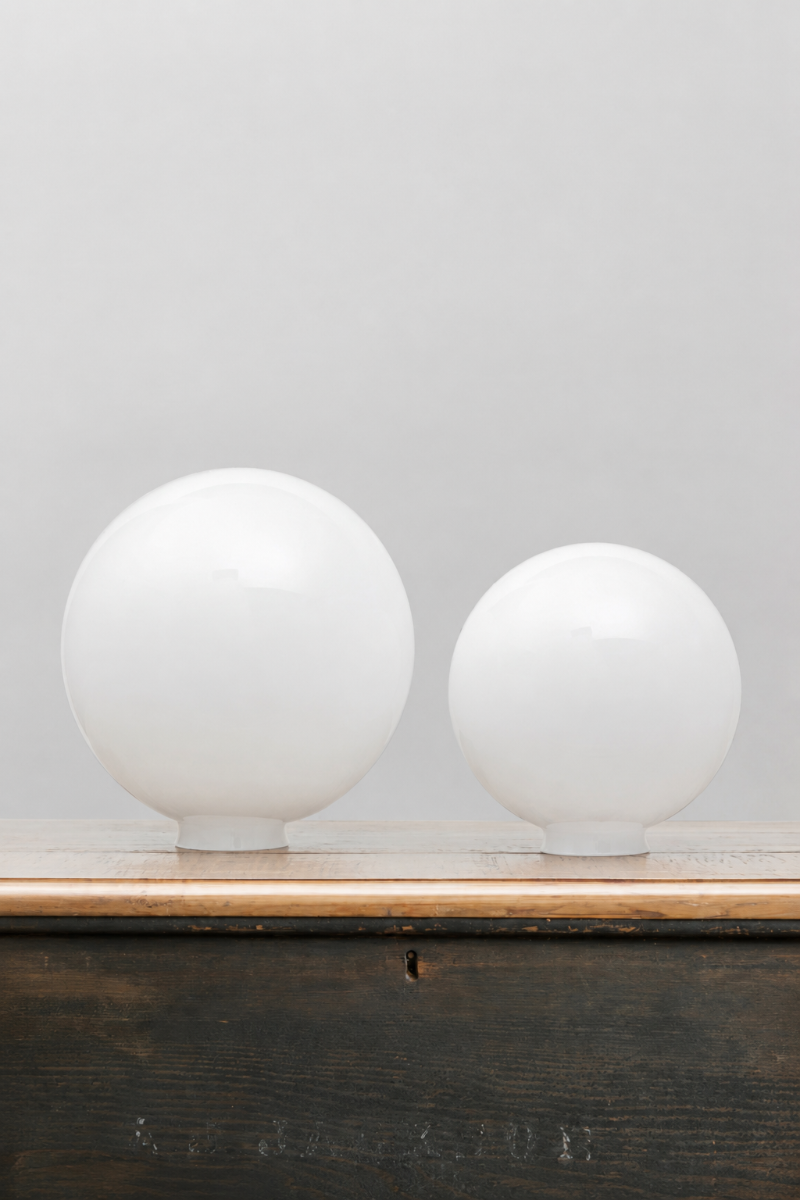 Medium and large opal glass ball shades, placed on a timber bench. 