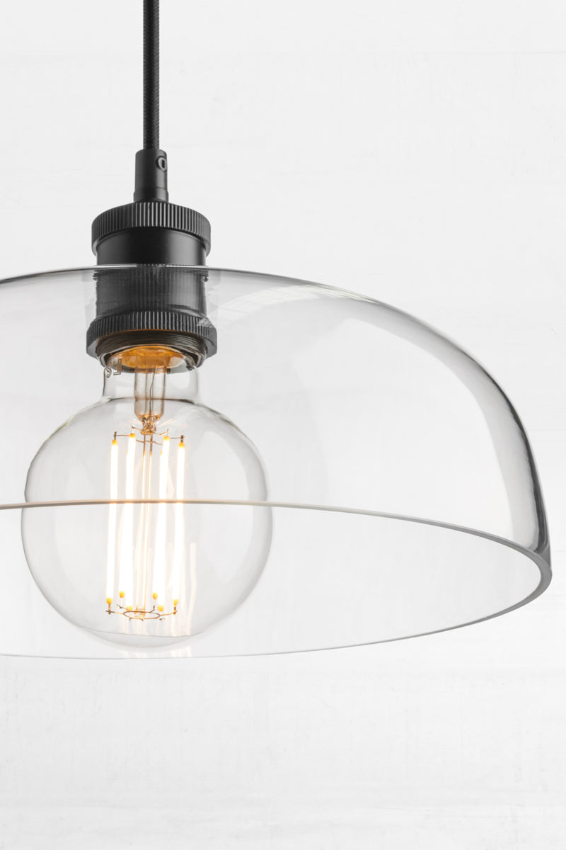 Close up of the clear glass shade with black hardware with a clear LED light bulb.