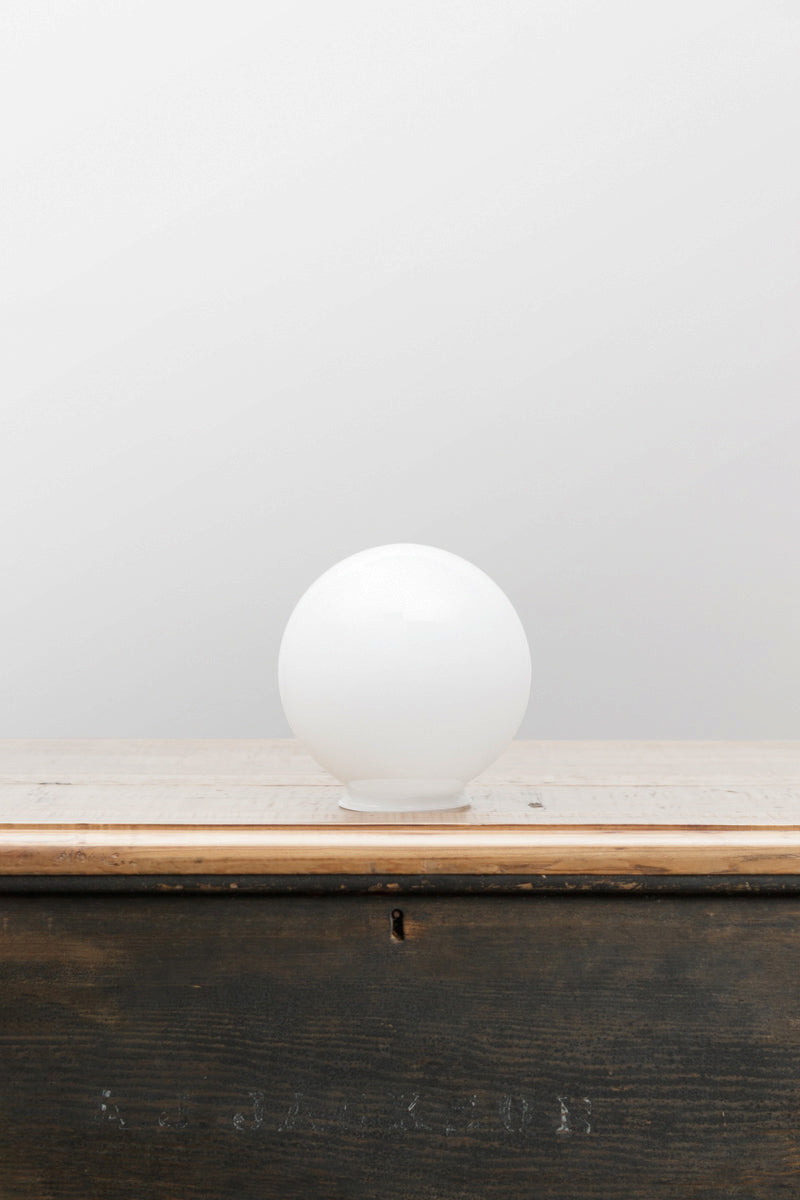 Small opal glass ball shade on a timber bench. 