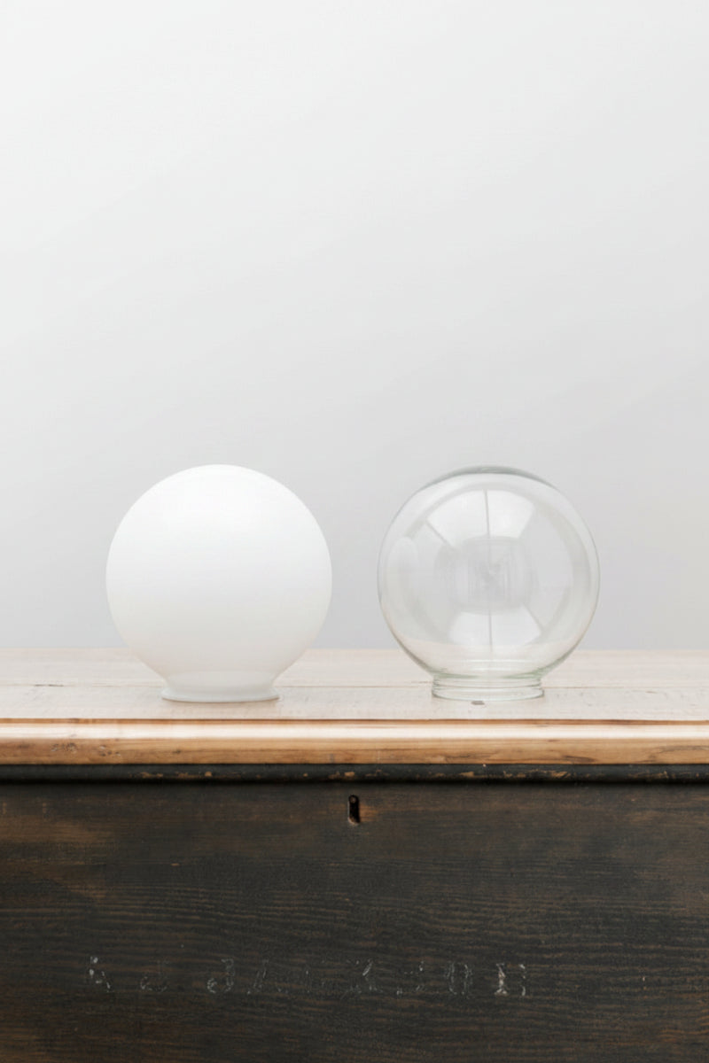 Small opal and clear glass ball shades on a timber bench. 