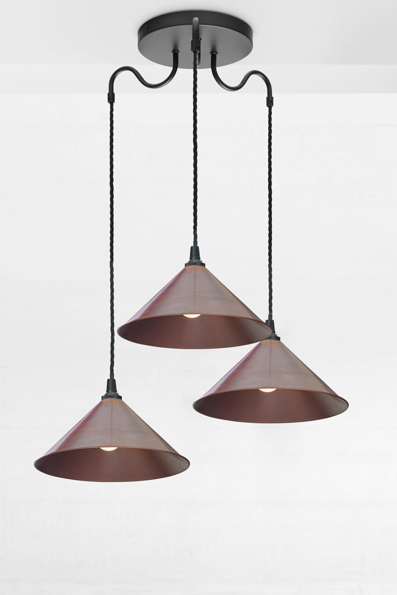 Front angled view of three large copper cone shades on a black gooseneck multi drop fixture.