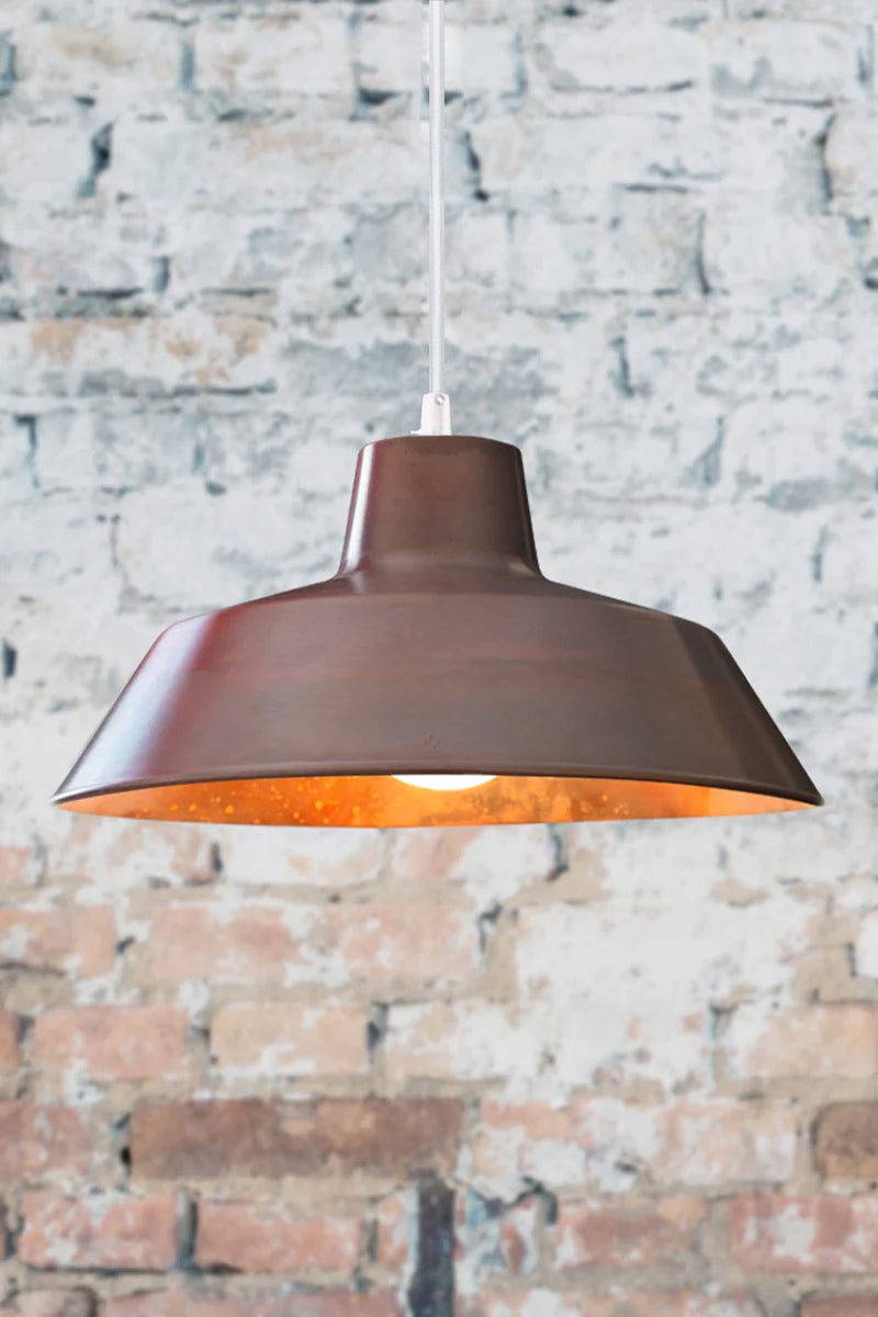 Aged copper factoery pendant light with white cord and light on. 
