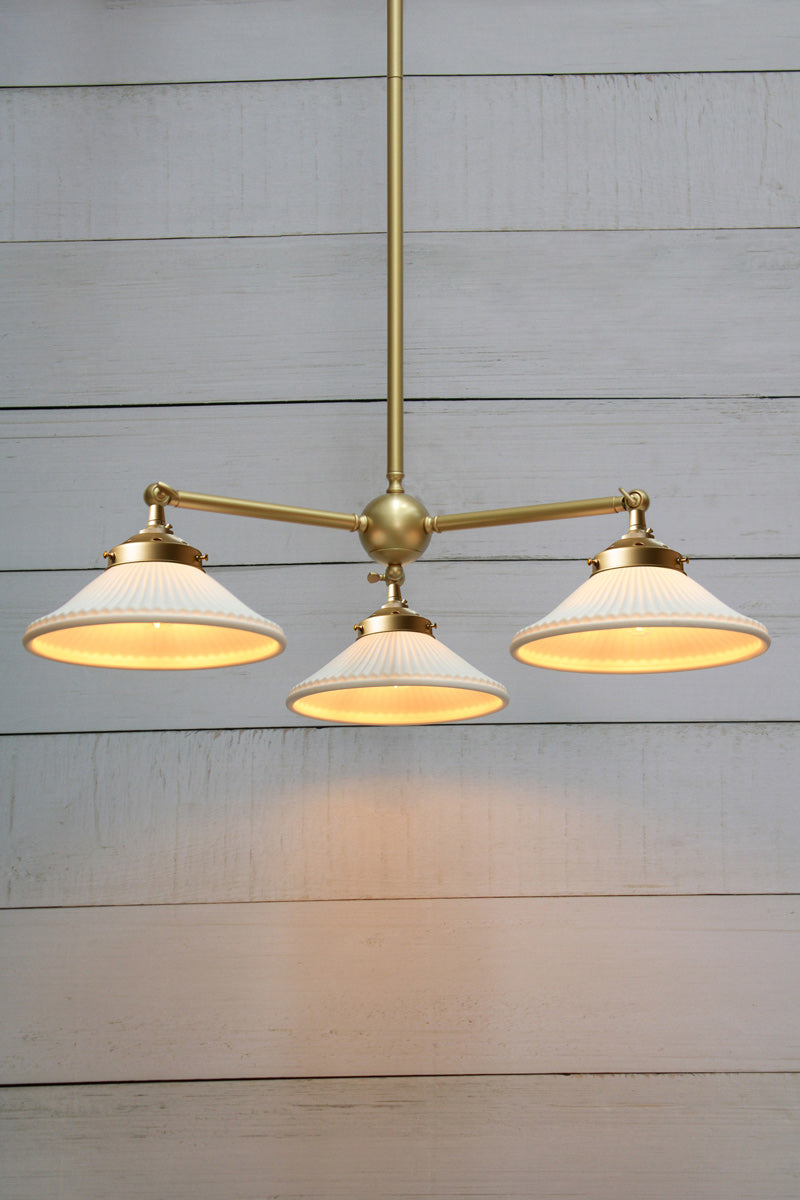 Triple straight arm chandelier in gold/brass with white ceramic pleated shades. 