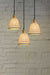 A 3-drop light chandelier featuring small ceramic shades and a gold/brass pendant cord.