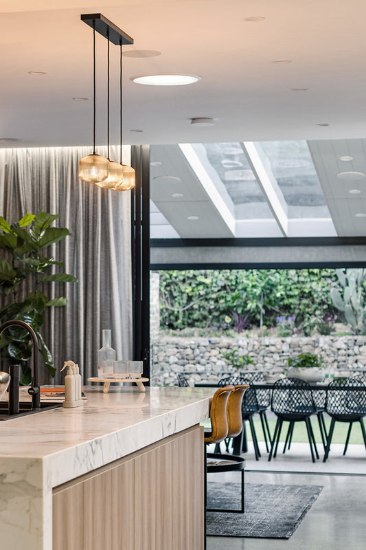 Thee reeded glass shades on linear ceiling mount in a modern kitchen space. 