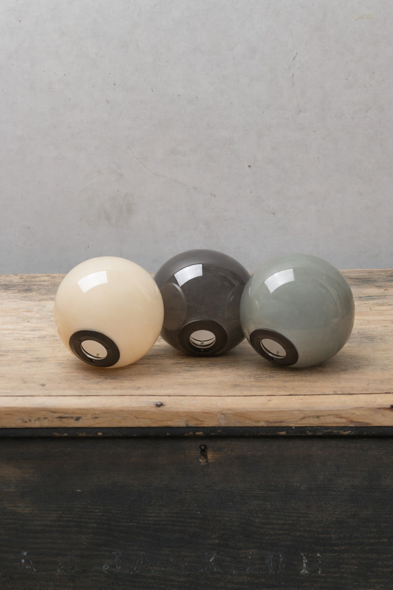 Thre glass ball shades in three finishes with black hardware on a timber bench