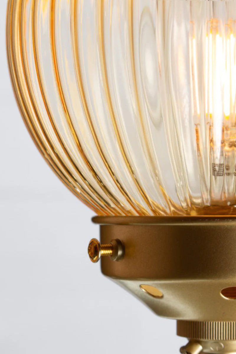 Close up of the gold brass five lamp linear chandelier with amber reeded glass ball shades. 