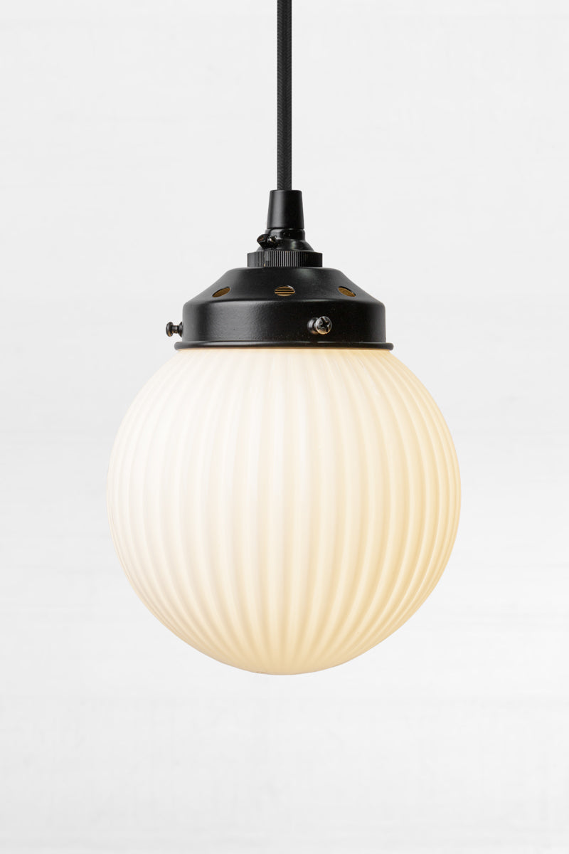Opal glass ball shade with vertical reeded detailing on a black pendant cord. 