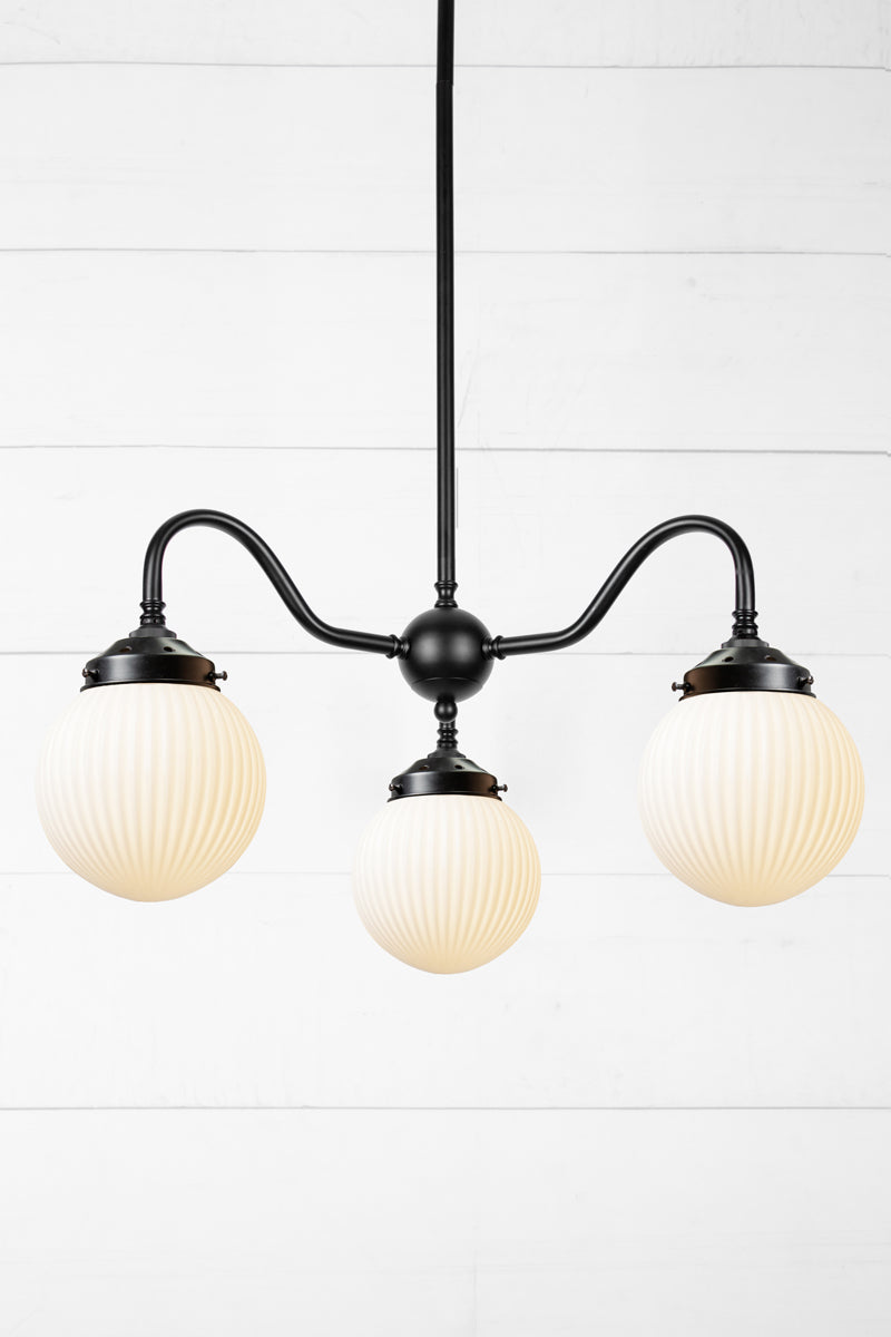 3 arm chandelier with gooseneck style arms in black with opal reeded glass ball shades. 