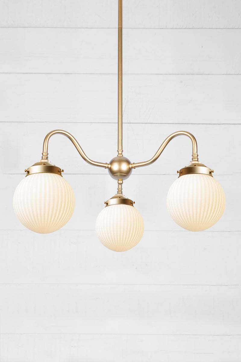 3 arm chandelier with gooseneck style arms in gold/brass with opal reeded glass ball shades. 