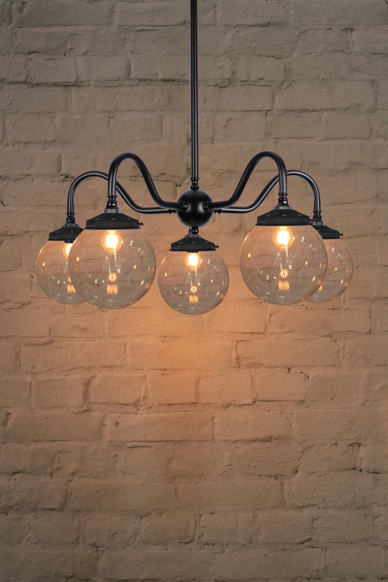 Small, clear glass ball shades on a five arm black gooseneck chandelier fixture. 