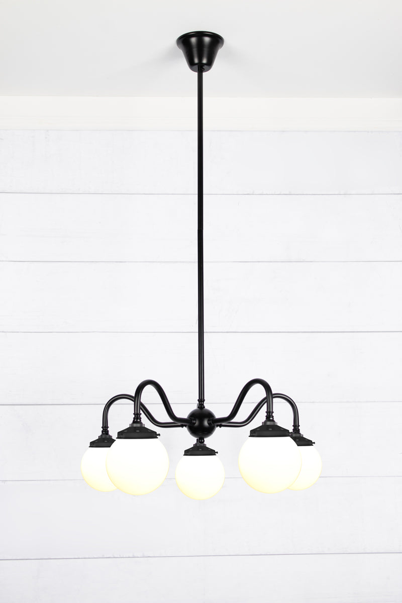 Small, opal glass ball shades on a five arm black gooseneck chandelier fixture. 