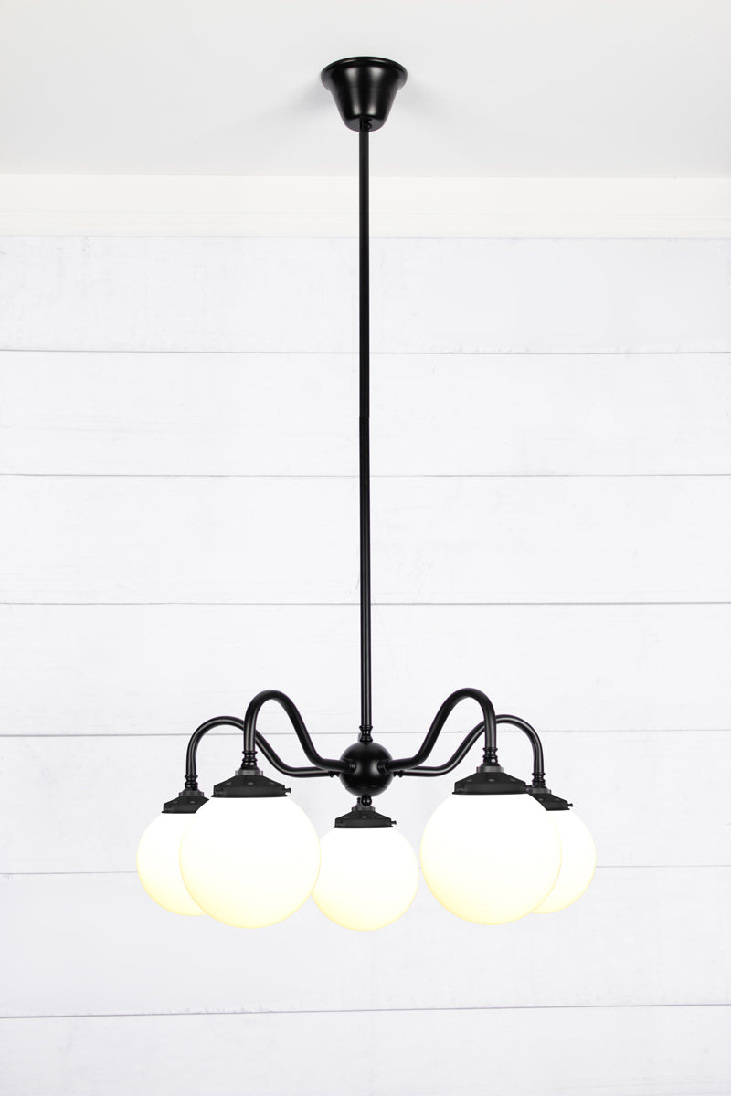 Medium, opal glass ball shades on a five arm black gooseneck chandelier fixture. 
