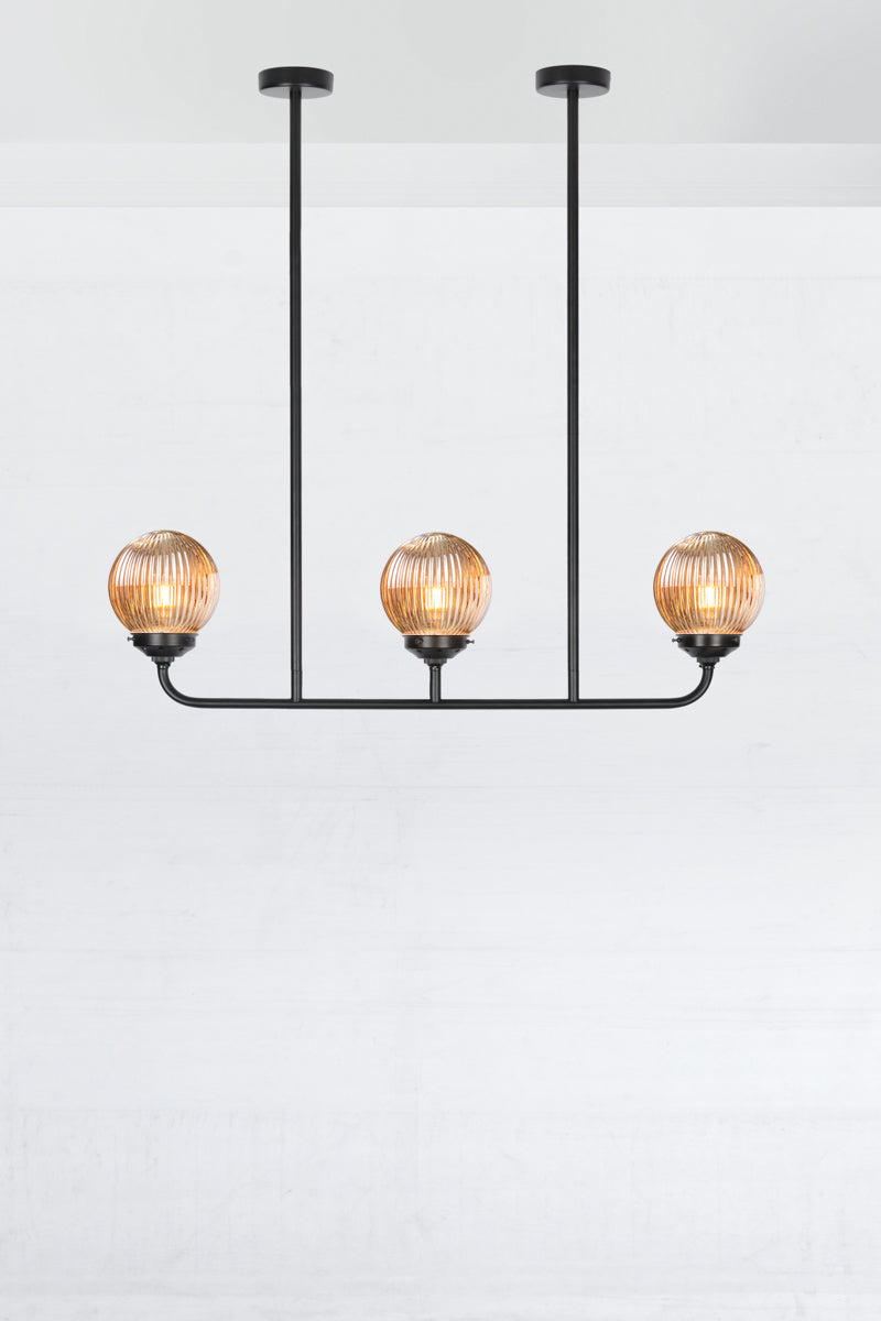 Black triple lamp linear chandelier with dark amber reeded glass ball shades. 