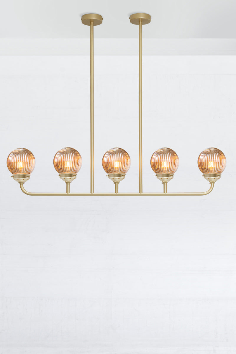 Gold/brass five lamp linear chandelier with dark amber reeded glass ball shades. 