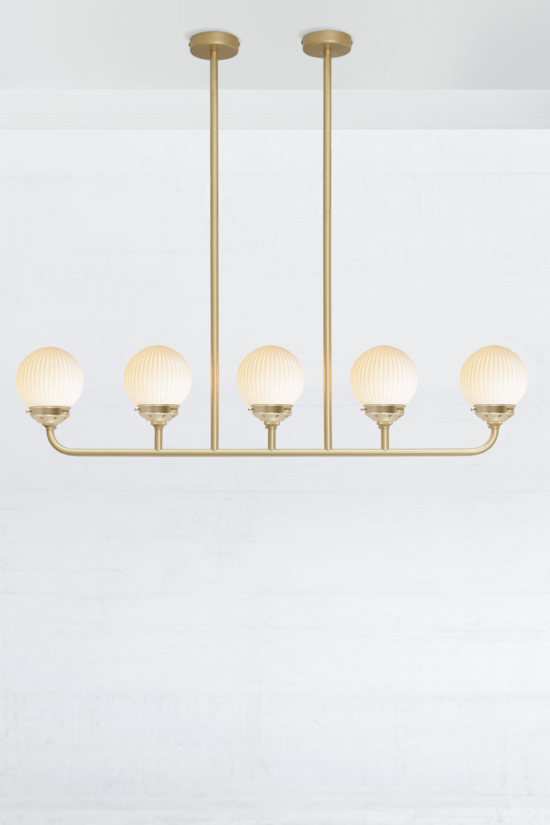 Gold/Brass five lamp linear chandelier with opal reeded glass ball shades. 