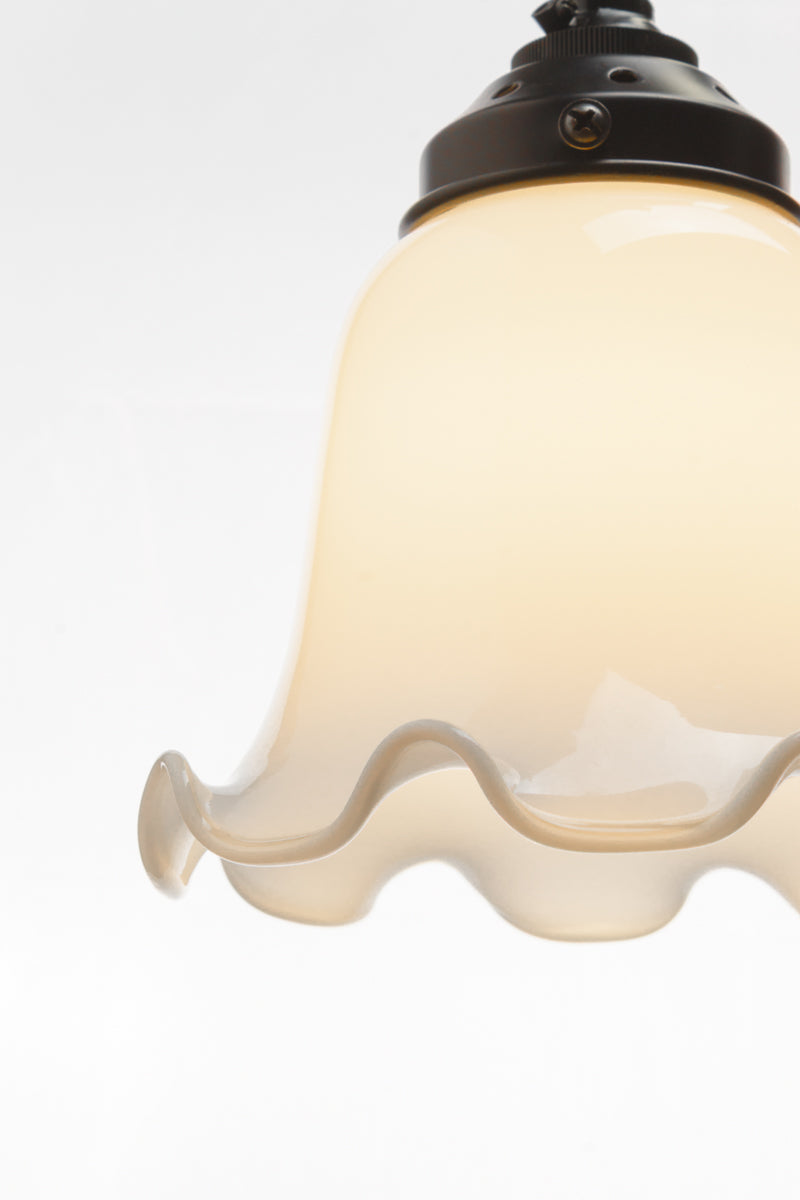 Close up of the opal glass bell shaped shades with scalloped edging. 