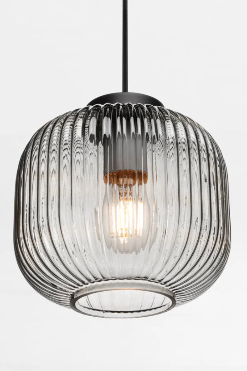Modern pendant light with grey ribbed glass shade on a white wall