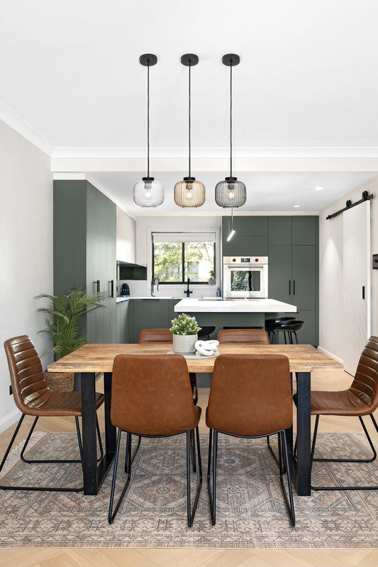Three reeded glass pendants in different finishes over a contemporary dining/kitchen space. 