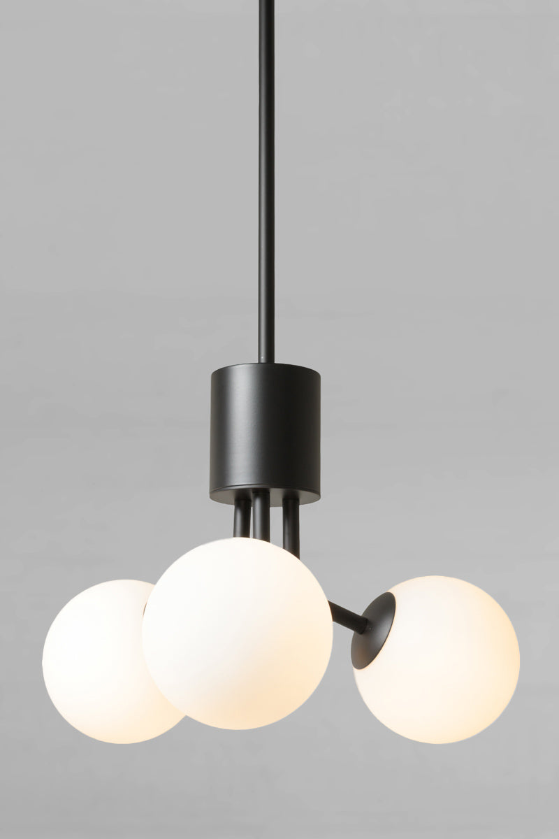 Modern three-light pendant chandelier with matte black metal hardware and glowing opal glass globes. Brooklyn Glass Orb Multi Light Pendant