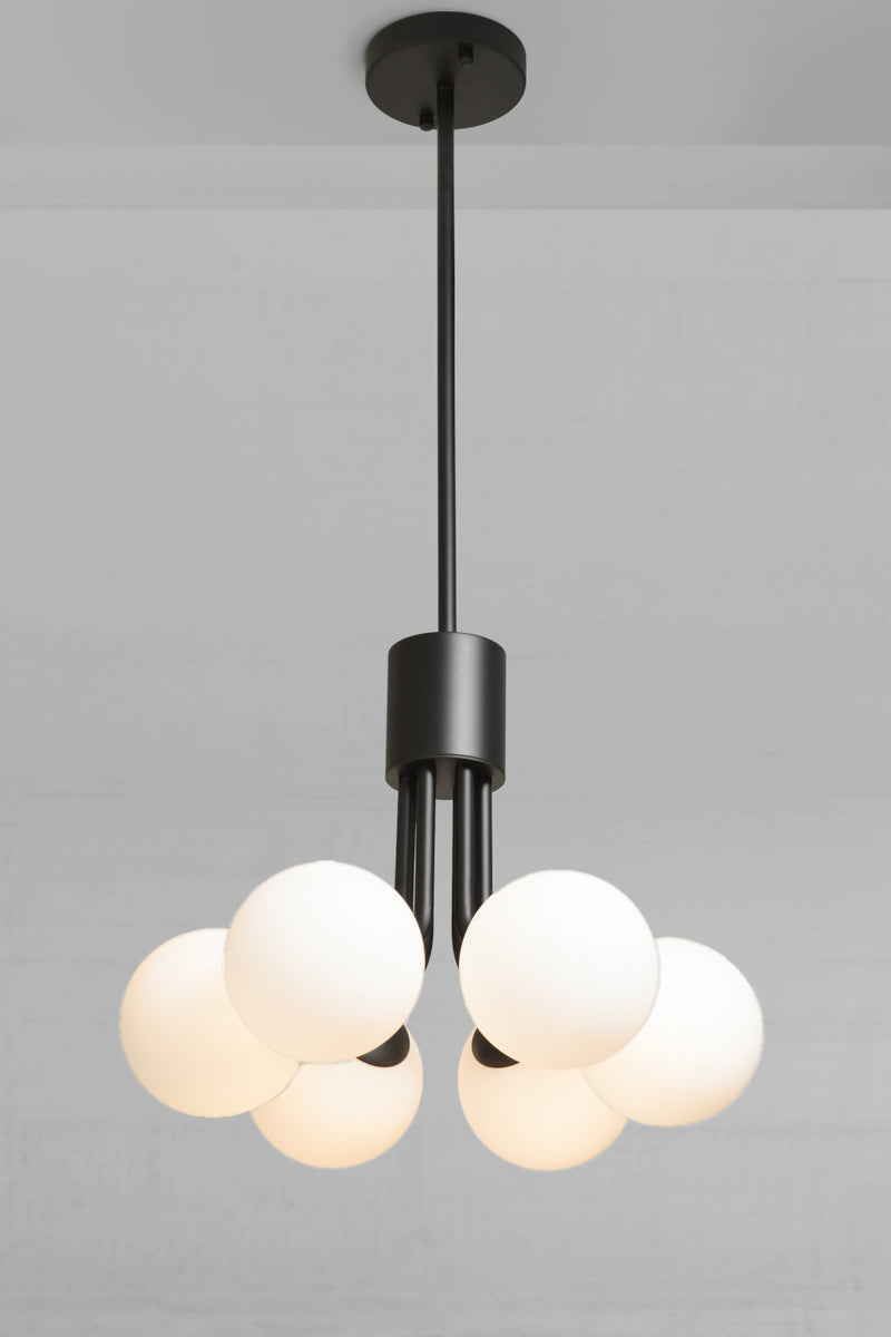 Modern multi-light pendant chandelier with a matte black metal frame and six glowing white spherical glass shades, suspended from a ceiling. Brooklyn Glass Orb 6 Light Pendant