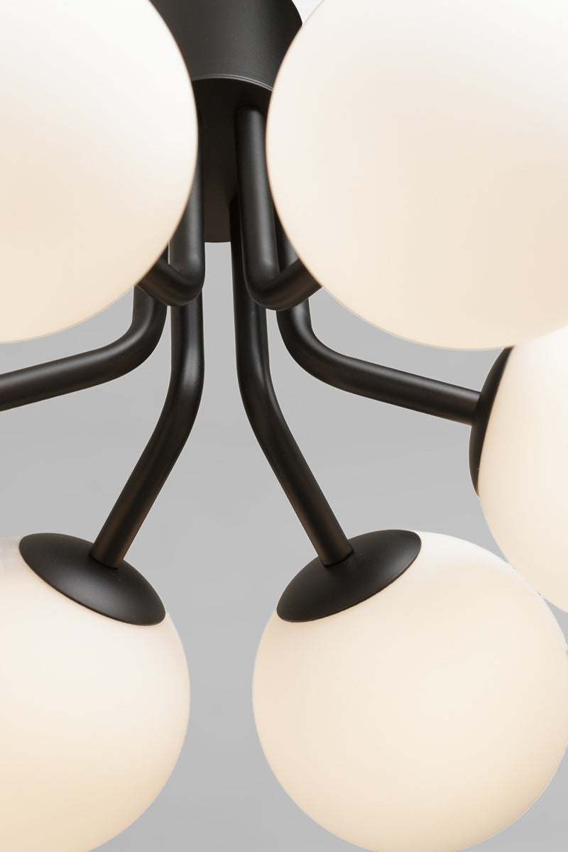 Close-up of a modern multi-light chandelier with matte black metal arms and glass orbs in opal glass finish