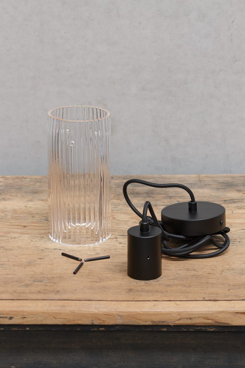 Uninstalled pendant light with black cord and clear glass shade. 