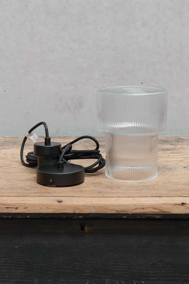 Uninstalled clear glass shade and black pendant cord. 